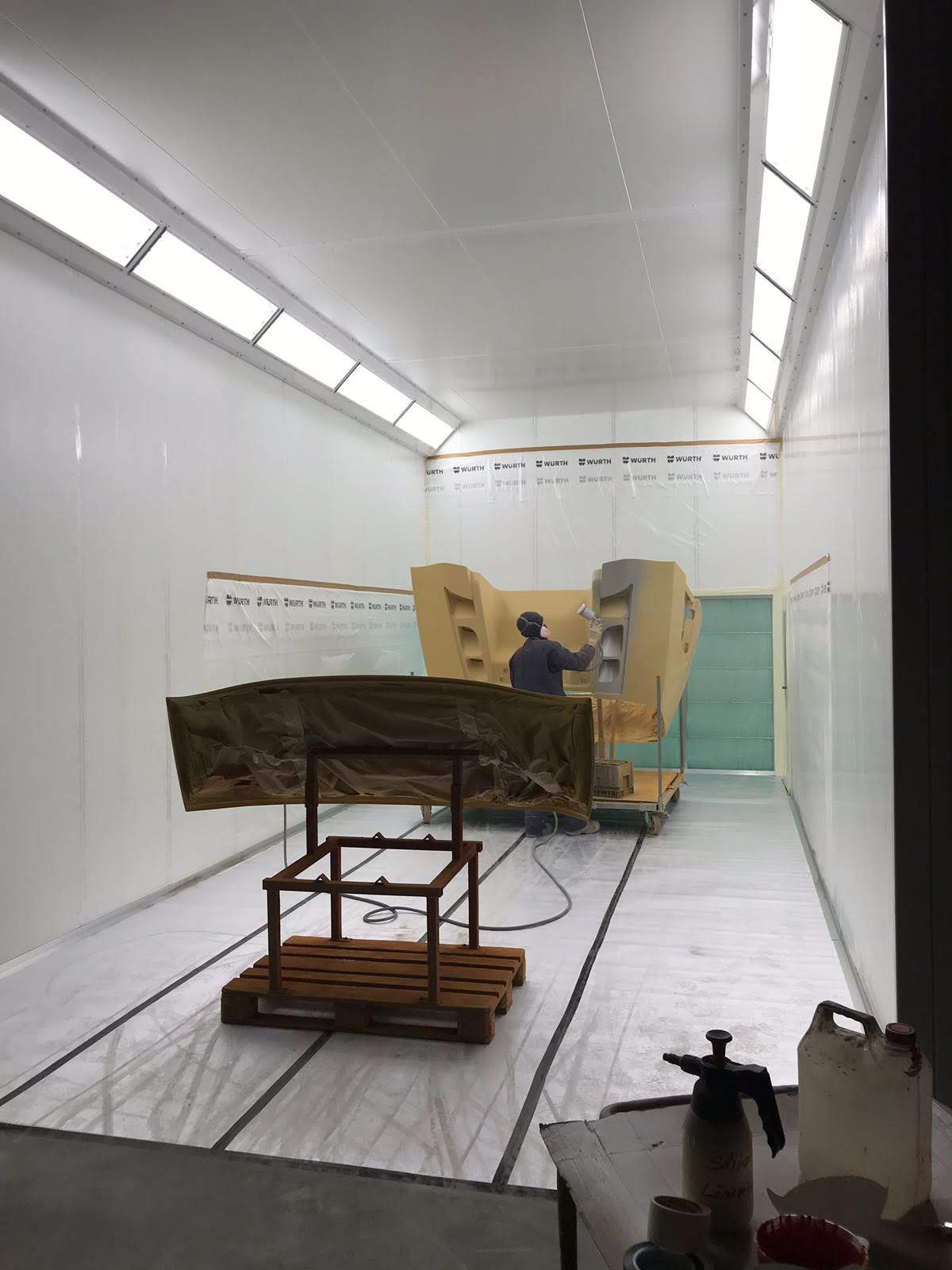 Painter applying primer to a vehicle front in the spray booth