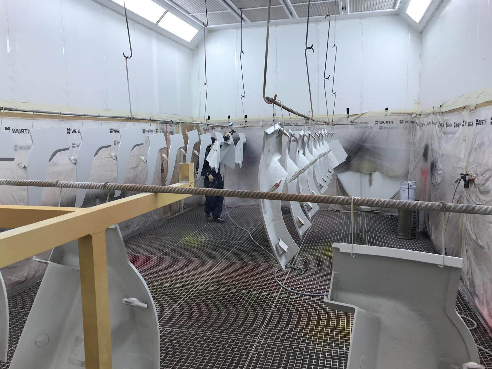 Series parts hanging on the beam in the spray booth during coating application